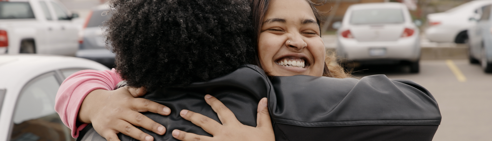 A smiling young woman hugs her mentor